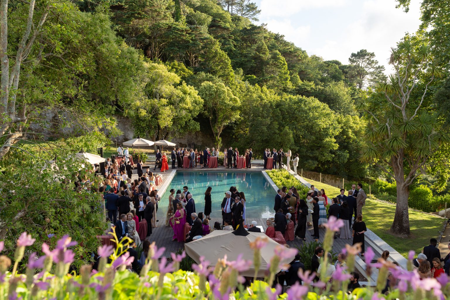 Festa ao ar livre num jardim, com mesas decoradas e convidados reunidos