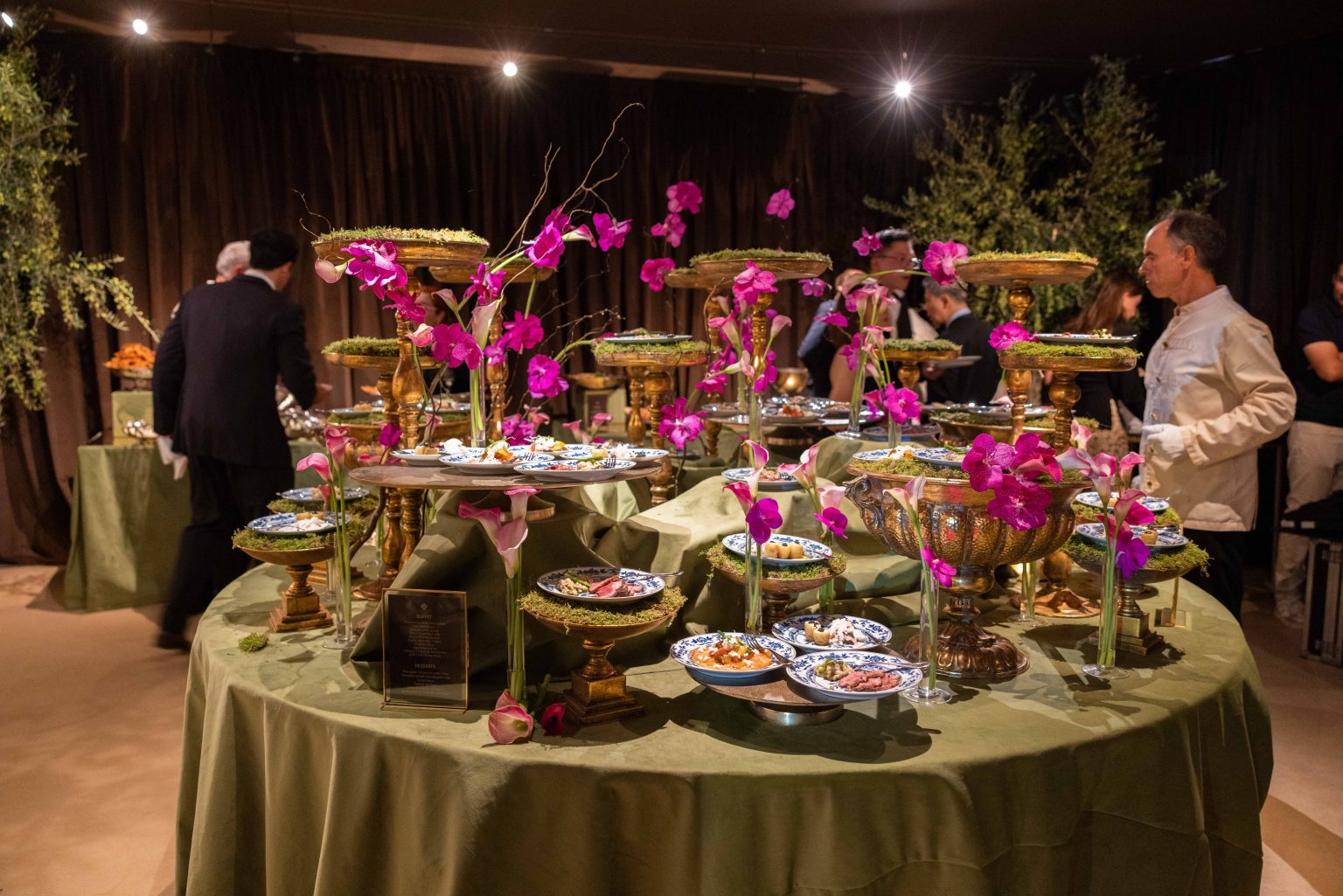 Mesa de buffet montada num espaço para festas, com decoração floral
